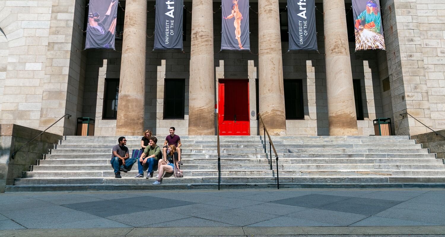 Five students sit on the steps outside Hamilton Hall