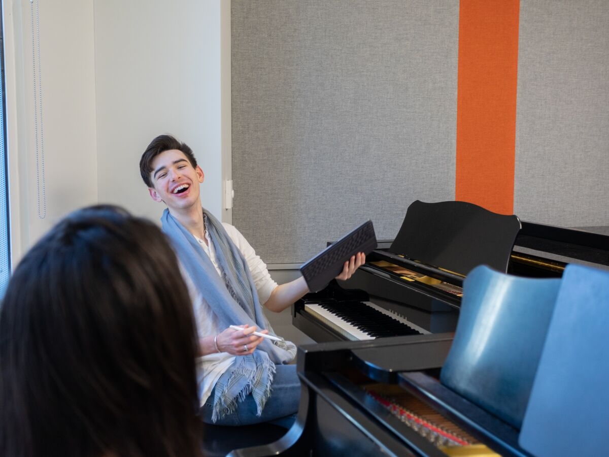 A student laughs during their private piano lesson.