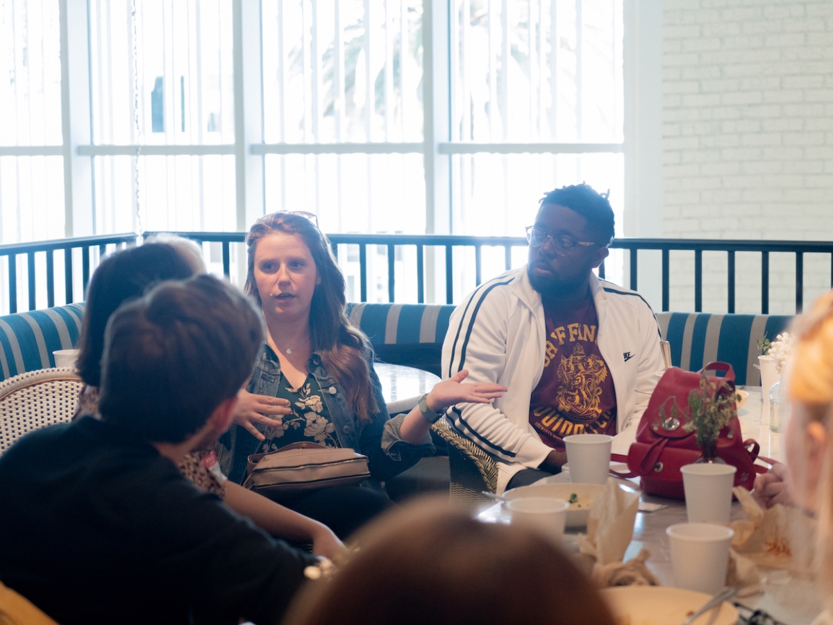Students and faculty sit around a brunch table and speak with alumni Lauren Deacon BFA ’09 (WFTV) and Darnell Brown Darnell Brown BFA ’10 (WFTV). 