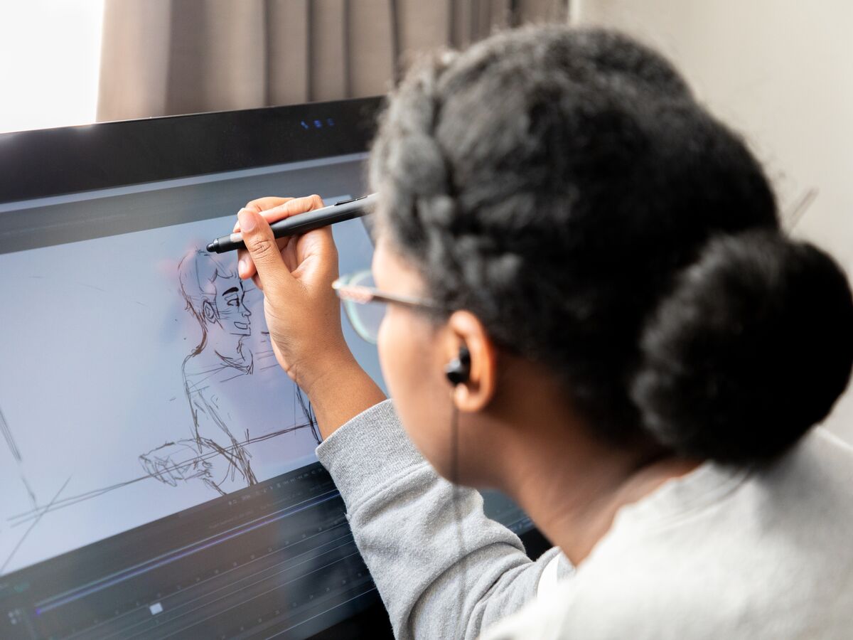 A student draws a figure in an animation class using their tablet.
