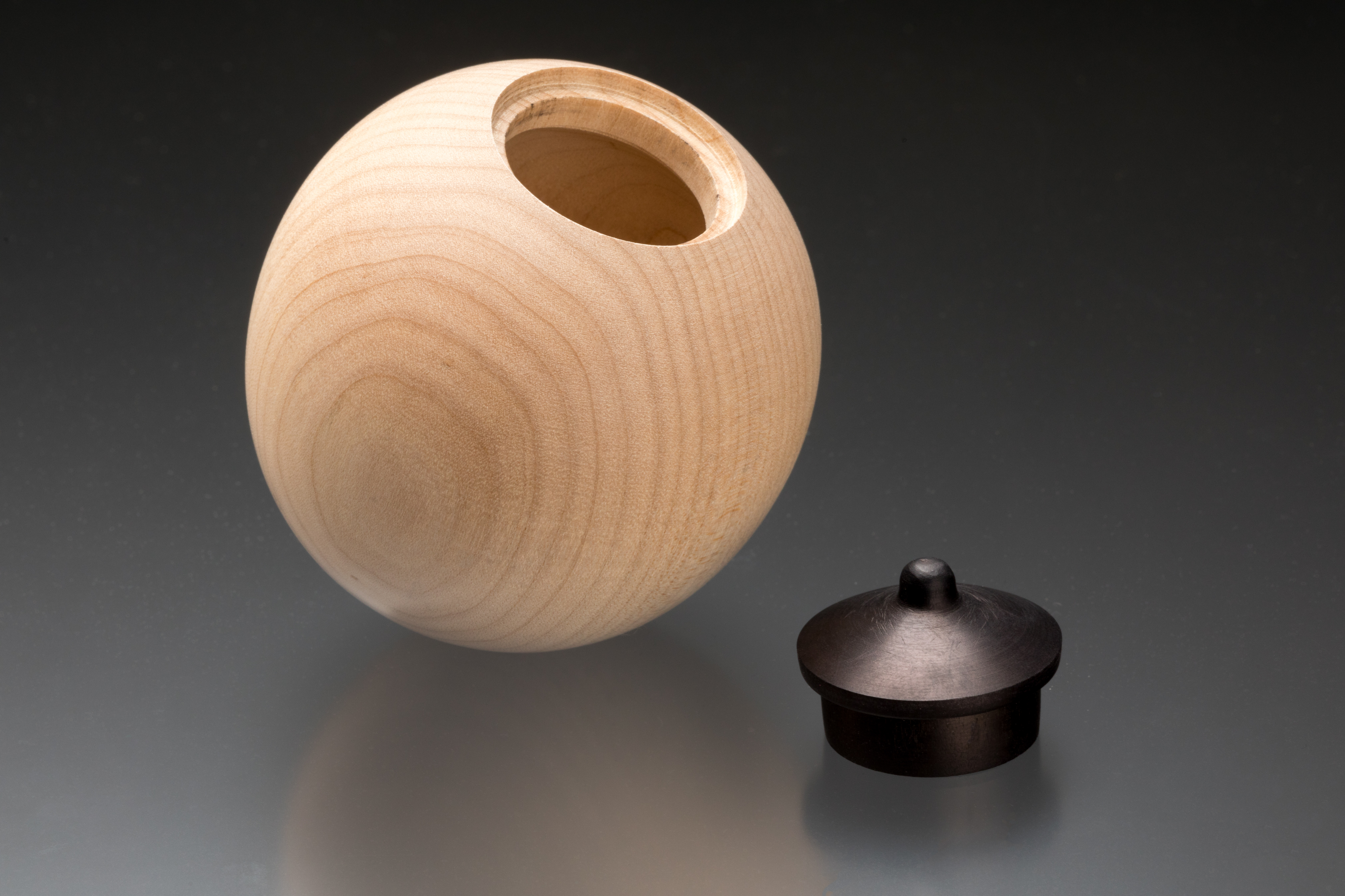 A tan ball with a hollow center and a black lid beside it 