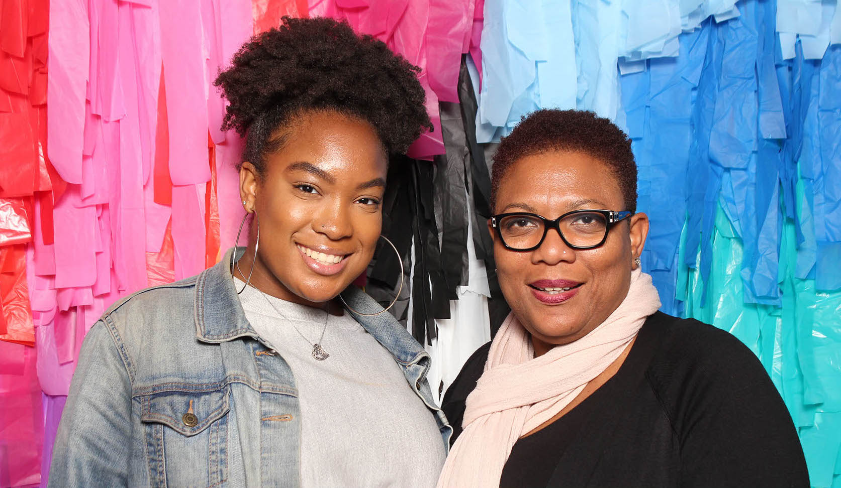 Mother and daughter pose in front of colorful crepe paper backdrop
