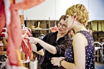 Laura Frazure works with a student on their sculpture