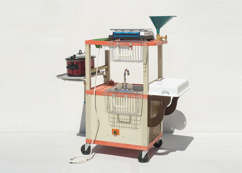 A mobile soap-making unit, which renders liquid soup from reclaimed cooking oil. Using wood, plastic, and metal, Shelley Spector fashioned the cart with an electrical hook-up, crock pot and sink, counter space, and storage for bottles and utensils, with the compact efficiency of a boat’s cabin.
