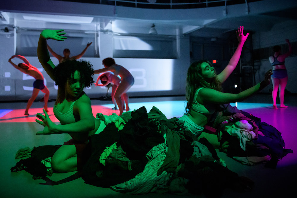 A photography of dancers in red, green and purple lighting. Photo credit: Ian Douglas
