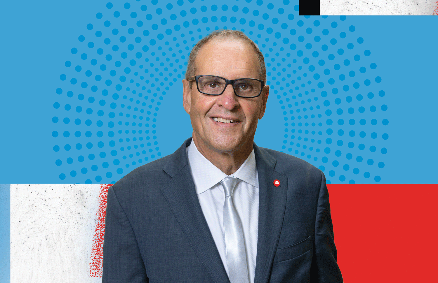 A portrait of UArts President and CEO, David Yager. He is wearing a silver tie, a dark blue suit jacket and has a red UArts logo pinned to his lapel. He is smiling slightly and has gray glasses. Behind him, a graphical collage of painterly red, white and blue color fields with blue dots emanating from the center.