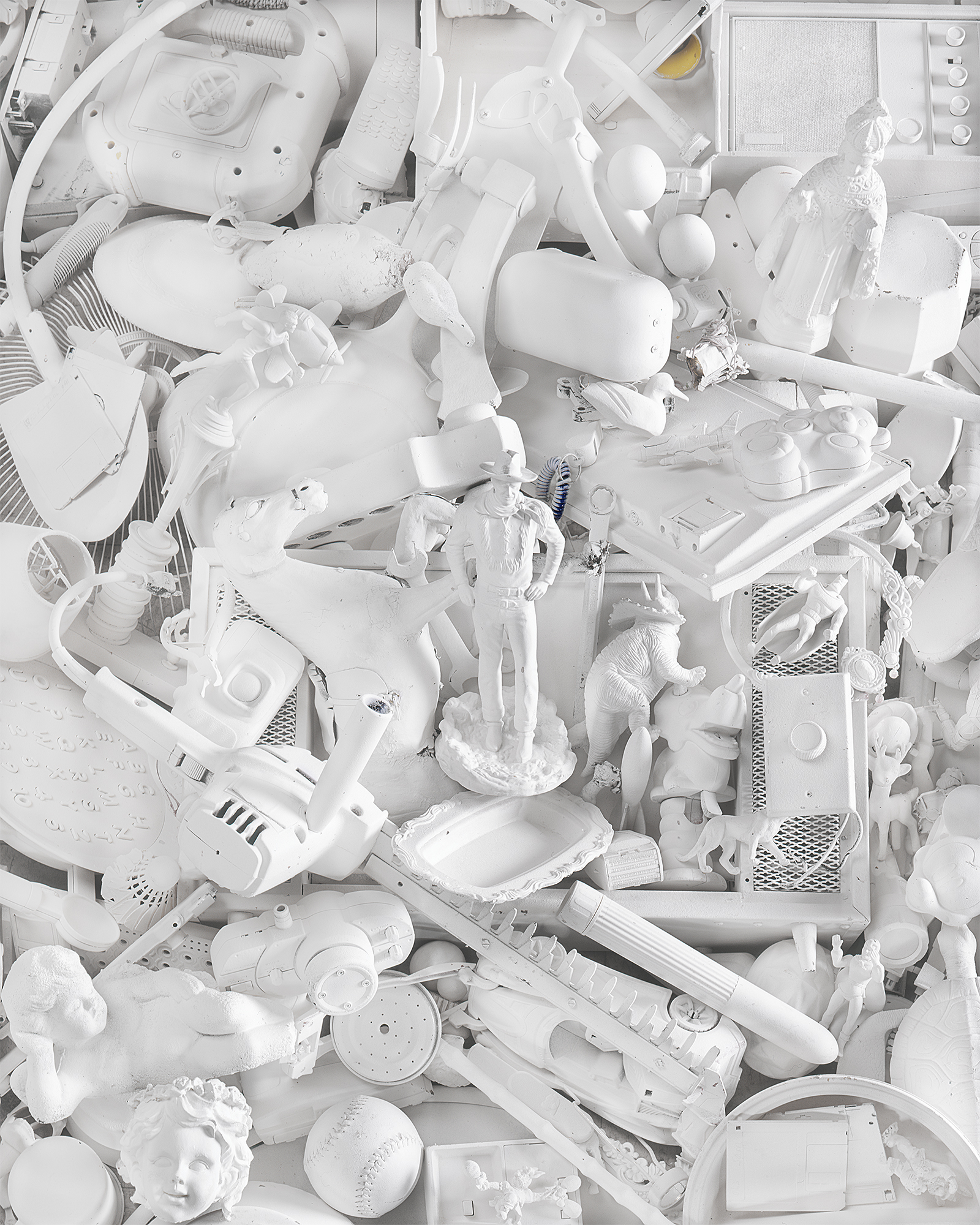 A tight shot of a pile of toys like dinosaurs and figures and dolls and baseballs all painted the same shade of white