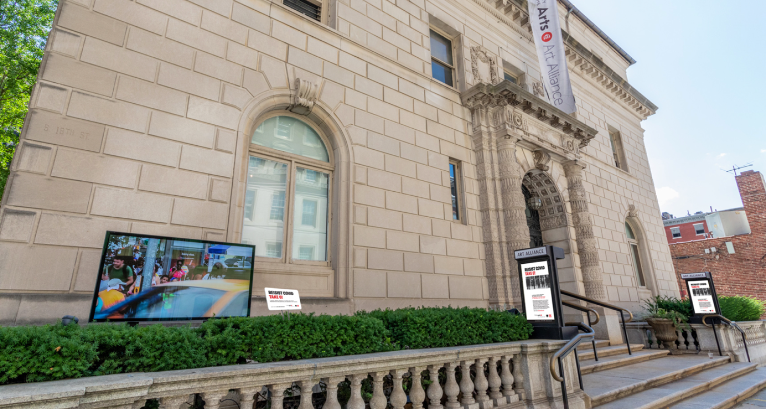Art Alliance exterior with a digital display screen installed in the foreground of the image on the left. A white banner reads Art Alliance at the University of the Arts in black text with a red UArts logo mark. 