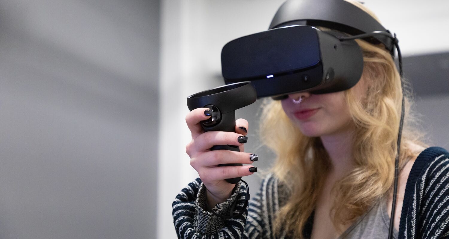 A student with blonde hair wearing a VR Headset, holding a VR controller.