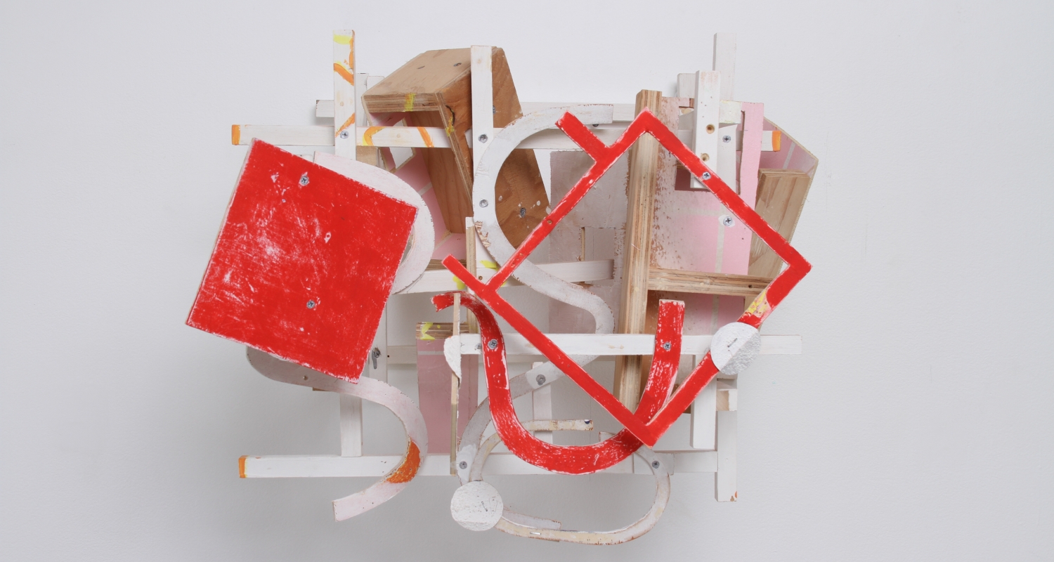 Image of sculpture on wall made of wood pieces painted white, red and pink and a few unpainted pieces