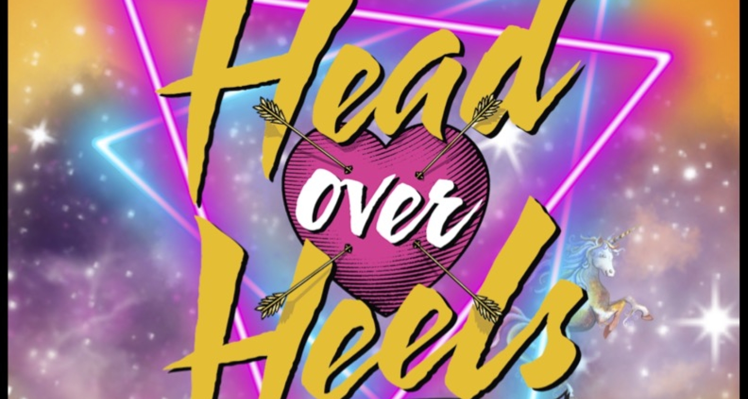 An orange and yellow glowing background with stars and a purple cloud in the middle. In the foreground, neon pink and blue triangles overlap. In the front it says "Head Over Heels A New Musical". "Over" is written inside a pink heart with arrows through it. 