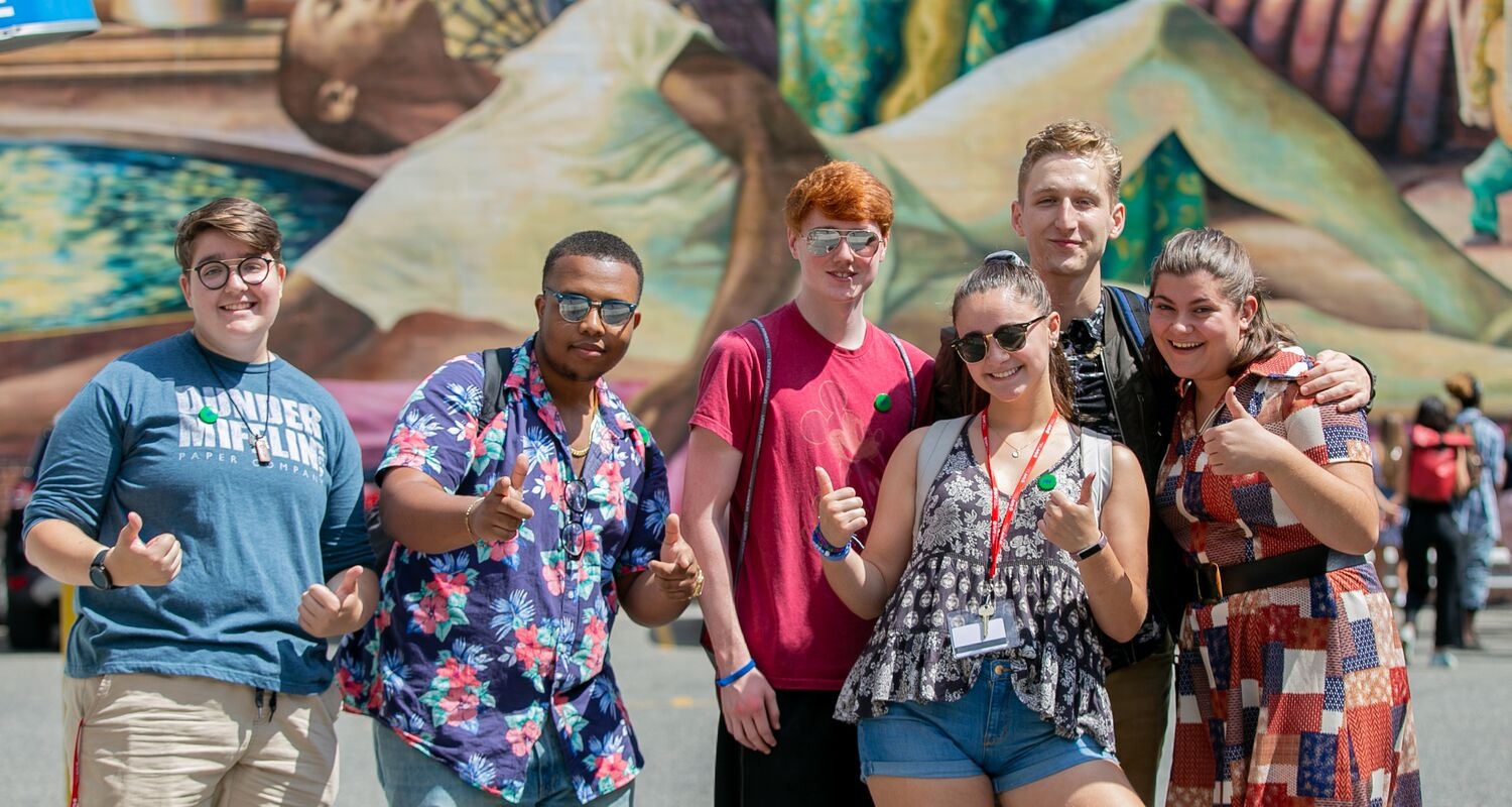 UArts students pose in front of mural art on campus