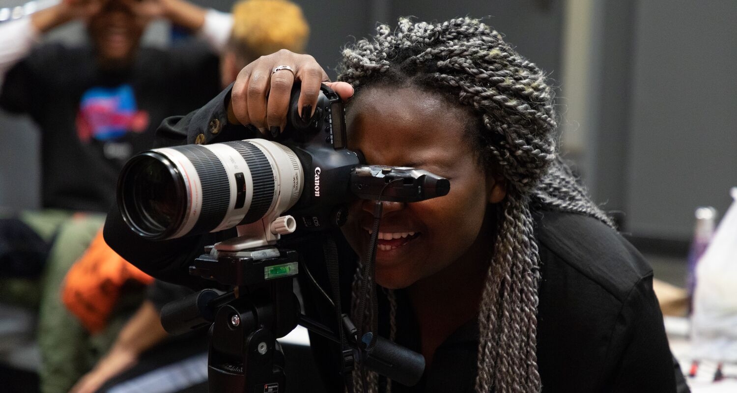 A student uses a DSLR camera to take a photo in the studio