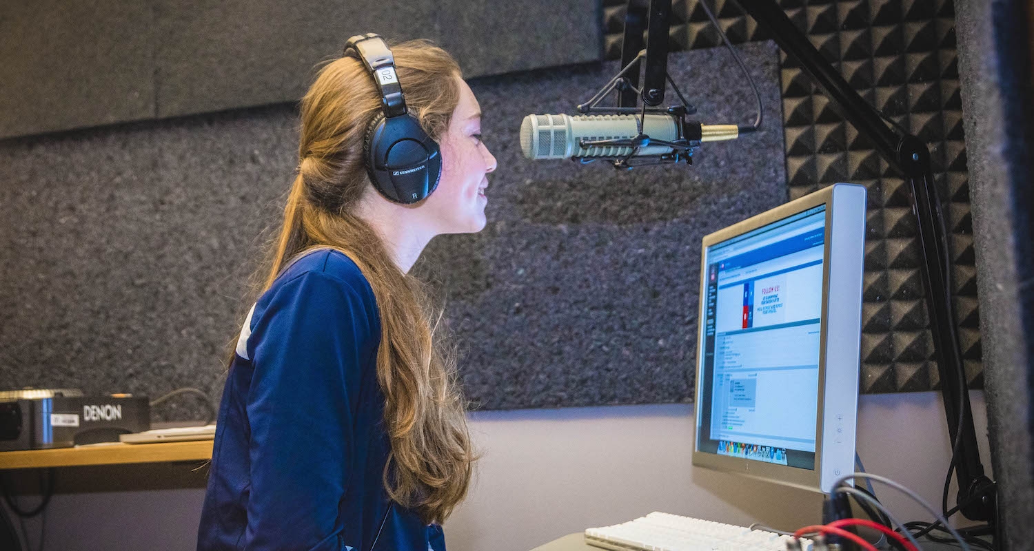 A student records their voice using a microphone and computer.