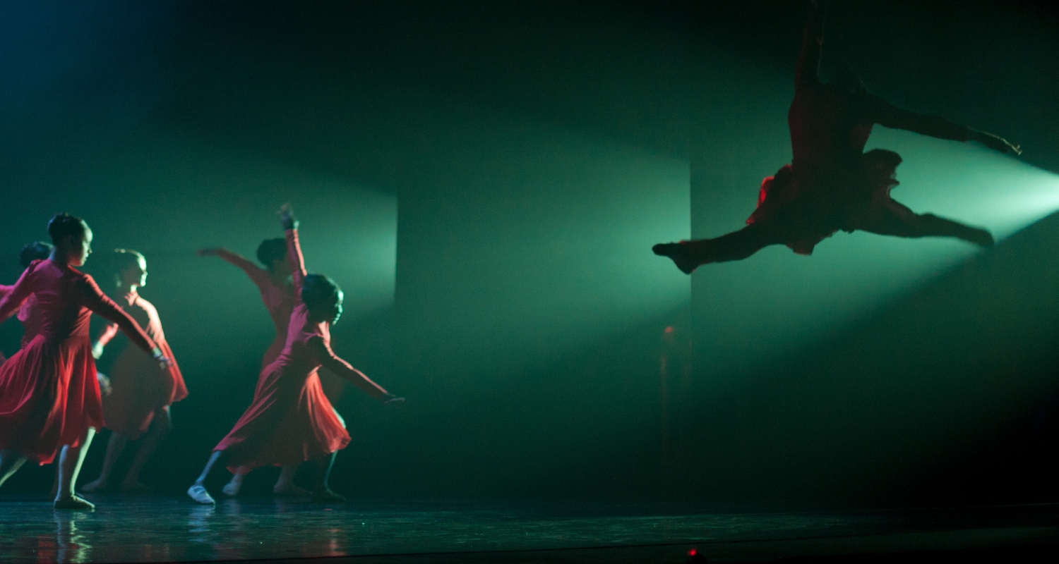 Dancers in red with green light and leaping