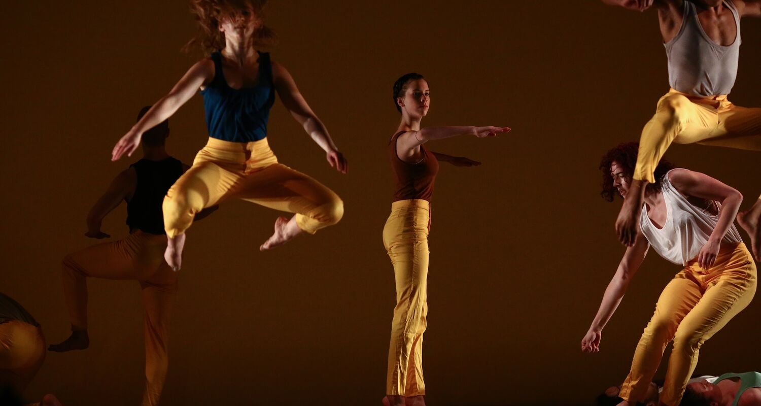 A candid image of several dancers wearing golden leggings performing PICTOGRAMS by Netta Yerushalmy 