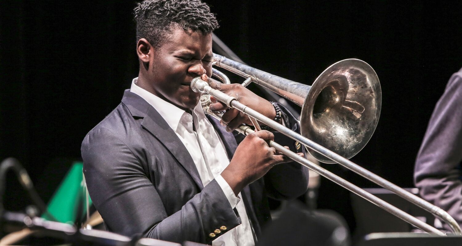 A trombone player performs on stage.