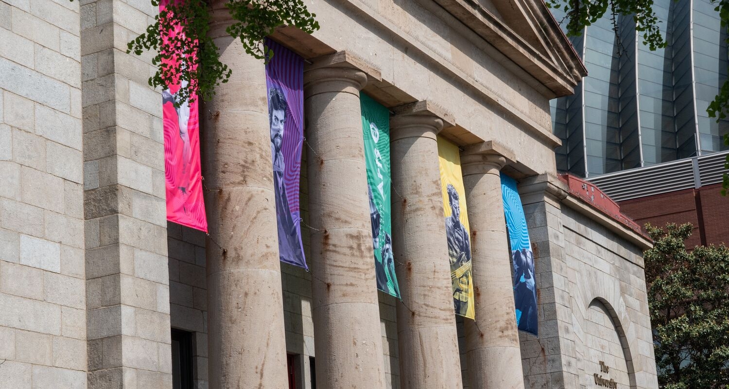 The pillars of Hamilton Hall decorated with pink and purple and green and yellow and blue banners
