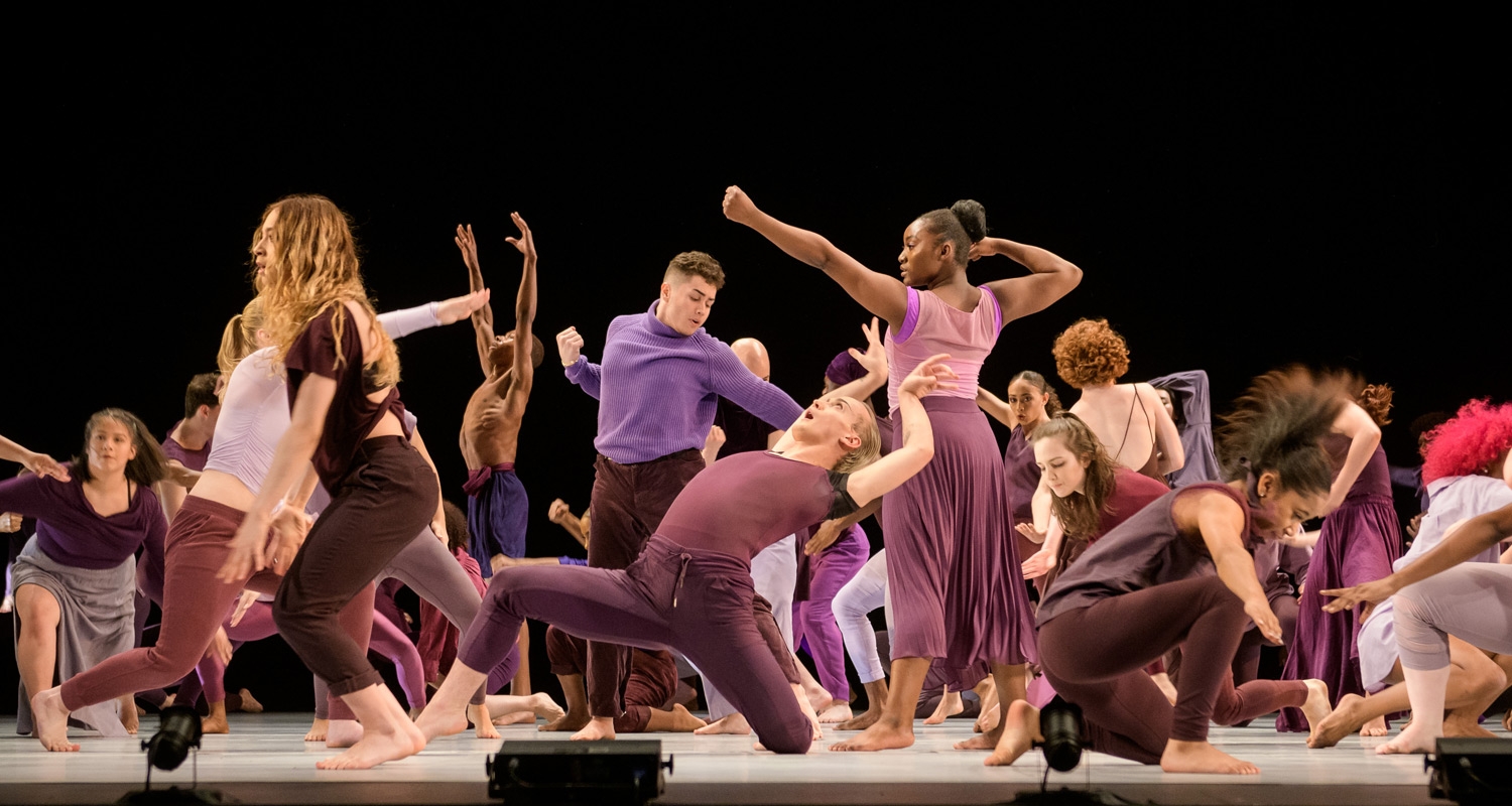 Dance students perform on a stage in color-blocked costumes