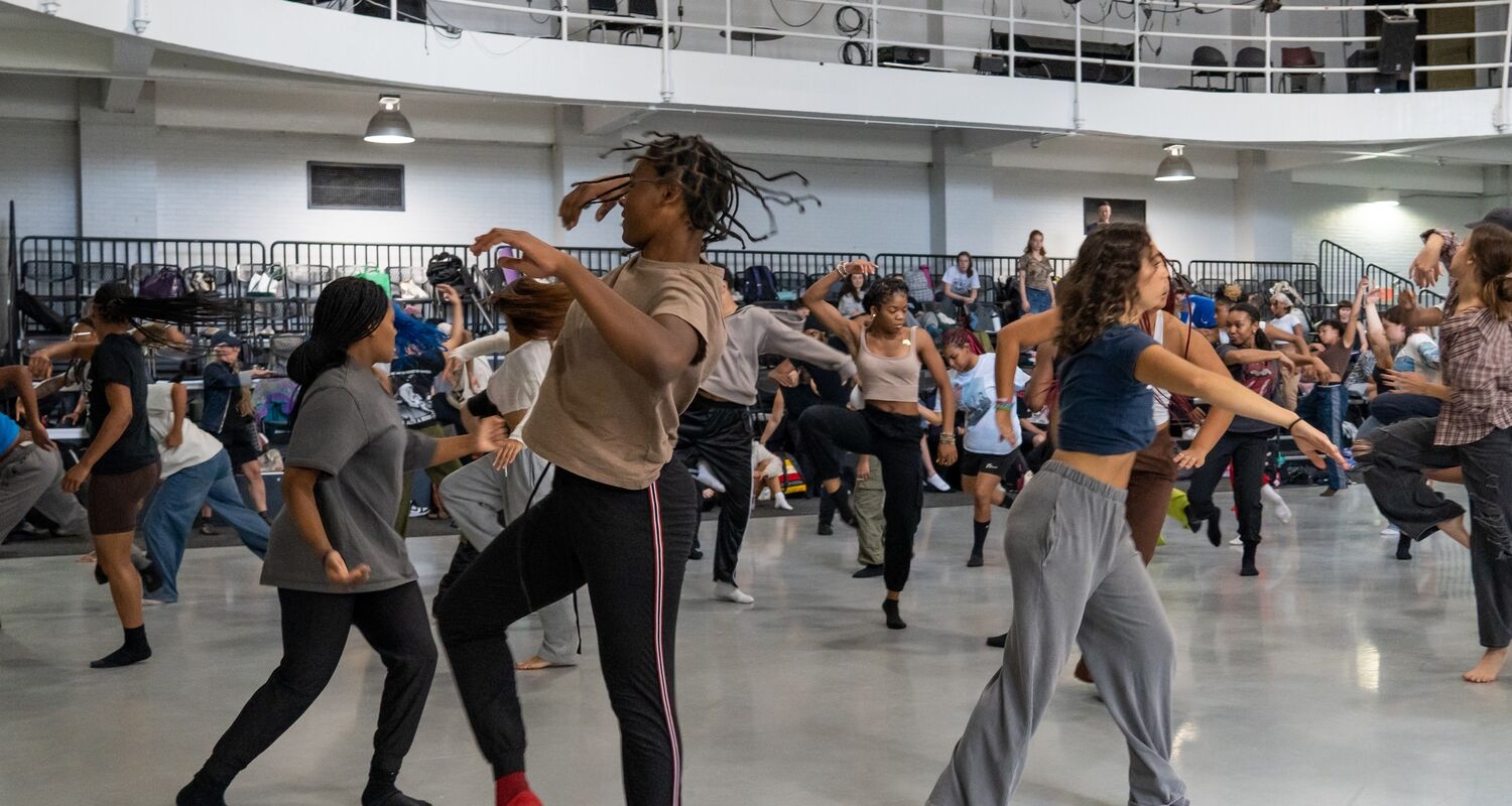 Dancers in a large group moving in different directions