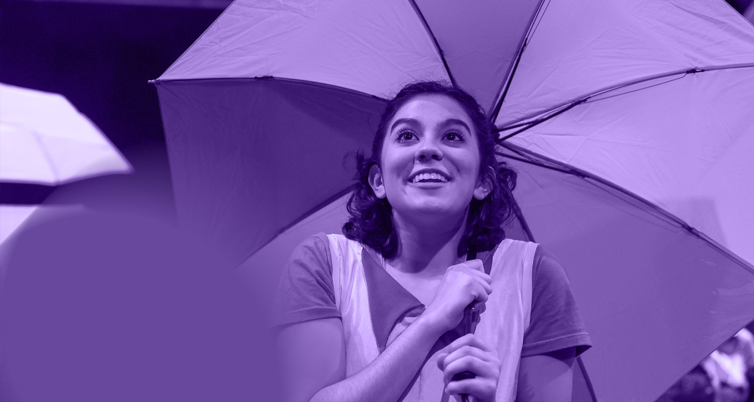 student performing on stage while holding an umbrella with purple wash overlay