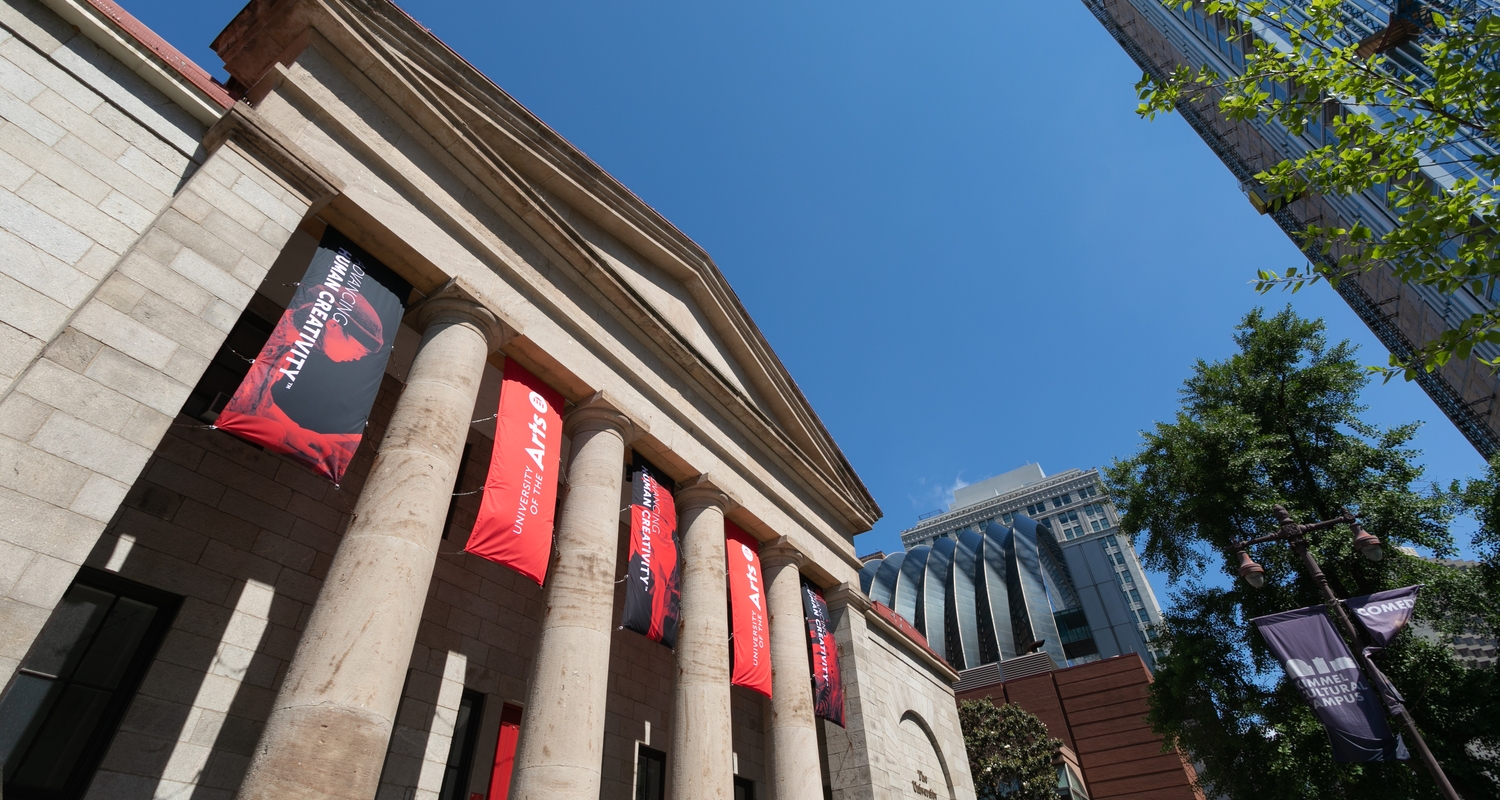 The pillars of Hamilton Hall decorated with black and red banners with a white UArts logo and the words Advancing Human Creativity