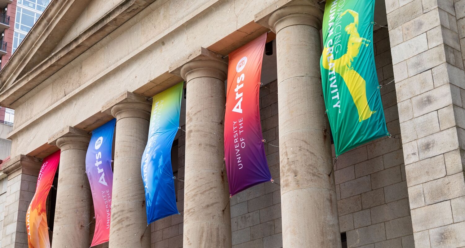 Hamilton Hall decorated with banners printed with gradients of blue and red ad green and magenta with the UArts logo in white type