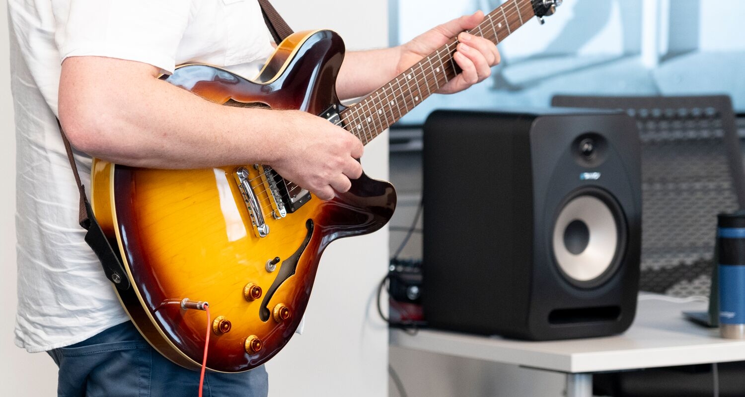 A closeup up of an electric guitar and an amplifier being played by an sms student