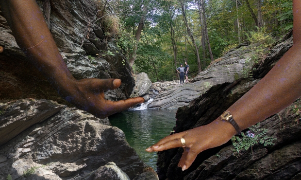 photo artwork showing two Black hands reaching towards one another against a landscape of trees, rocks and water