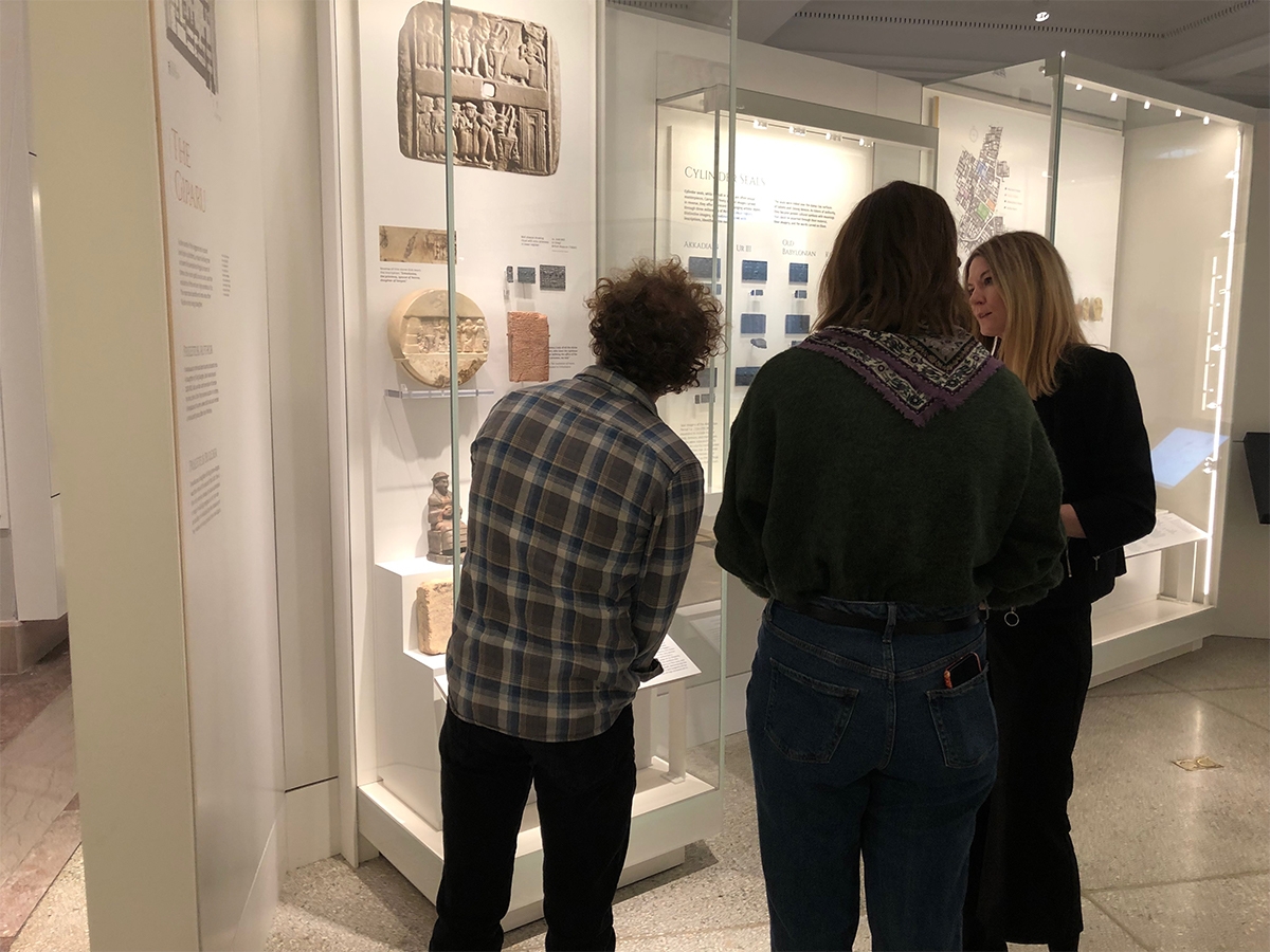 Two students look at an artifact at the Penn Museum while listening to a tour guide.