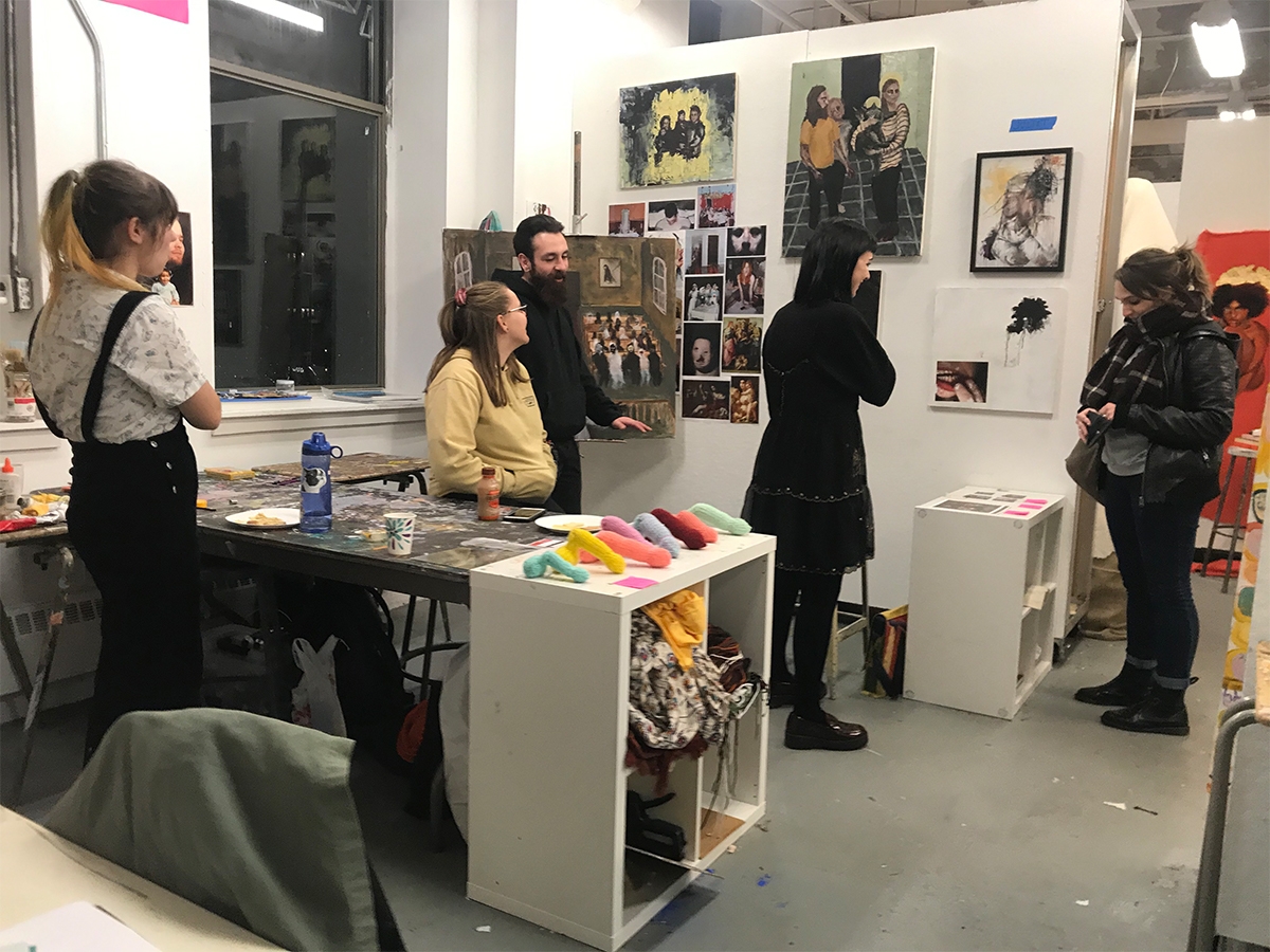 Four students walk through the painting studios during an open studio night.