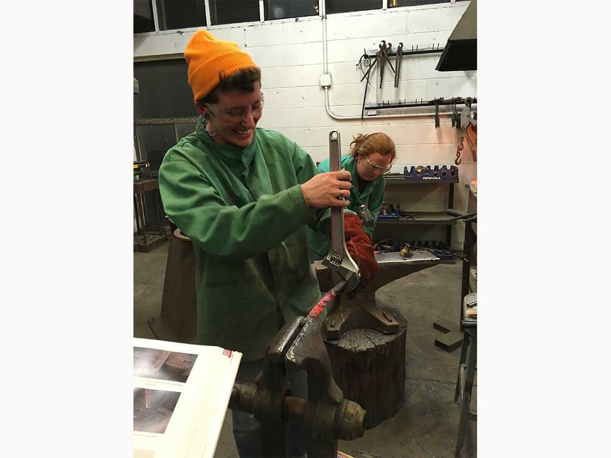 Students use a large wrench to bend fired metal