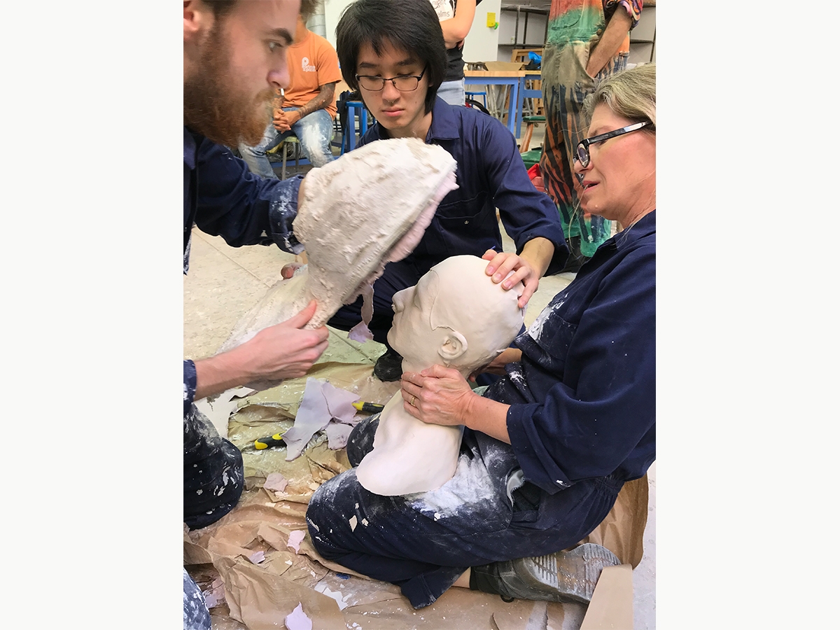 Sculpture students and faculty work together to remove a bust from the mold