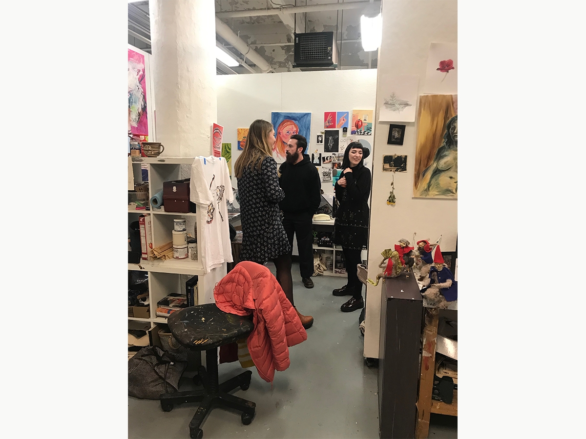 Three students walk through the painting studios during an open studio night.