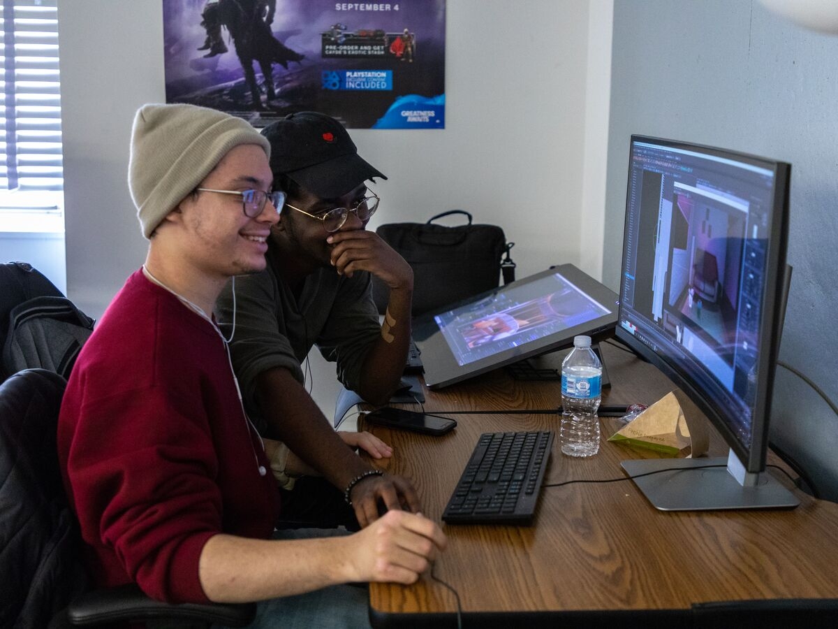 Two students work together using a computer and tablet to create an animation project in the Game Art program.