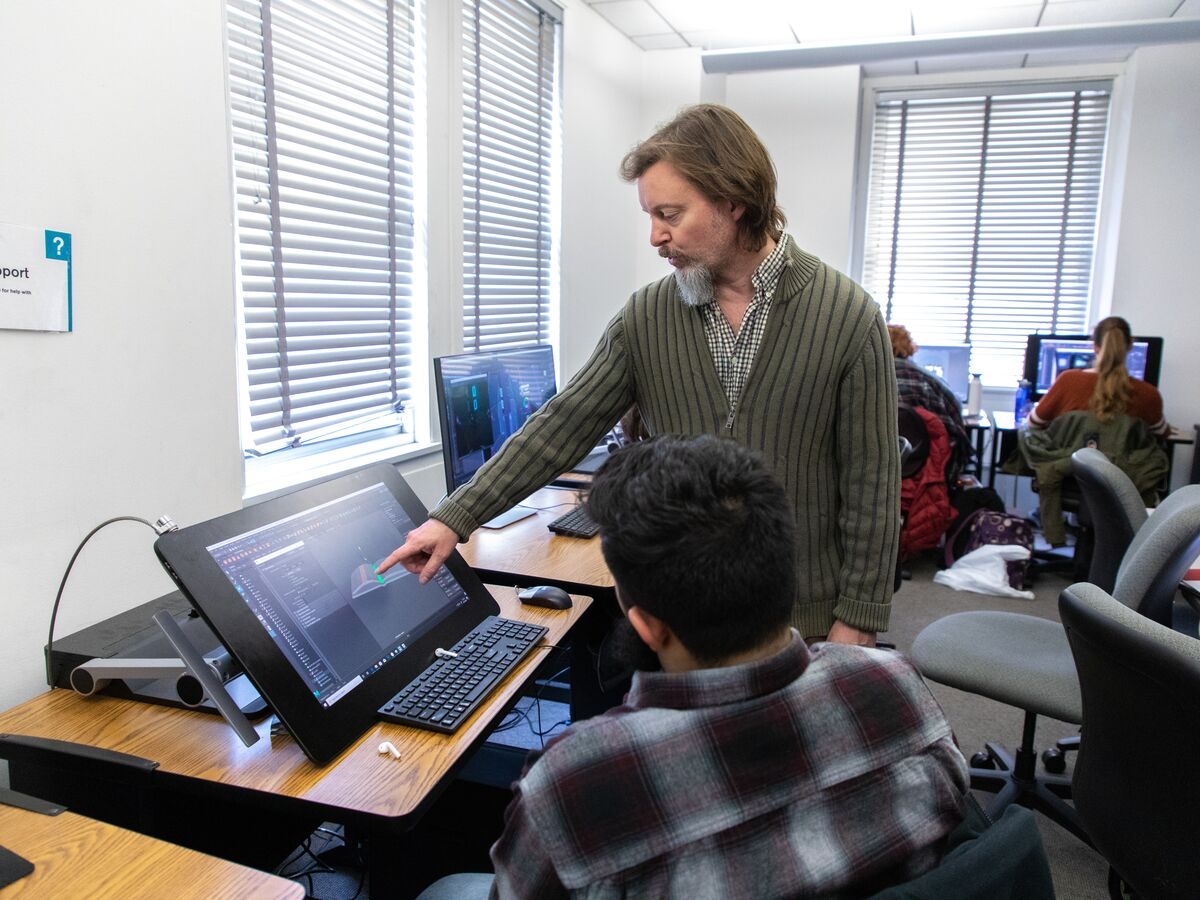 A student and faculty member use a tablet to work on an animation project.