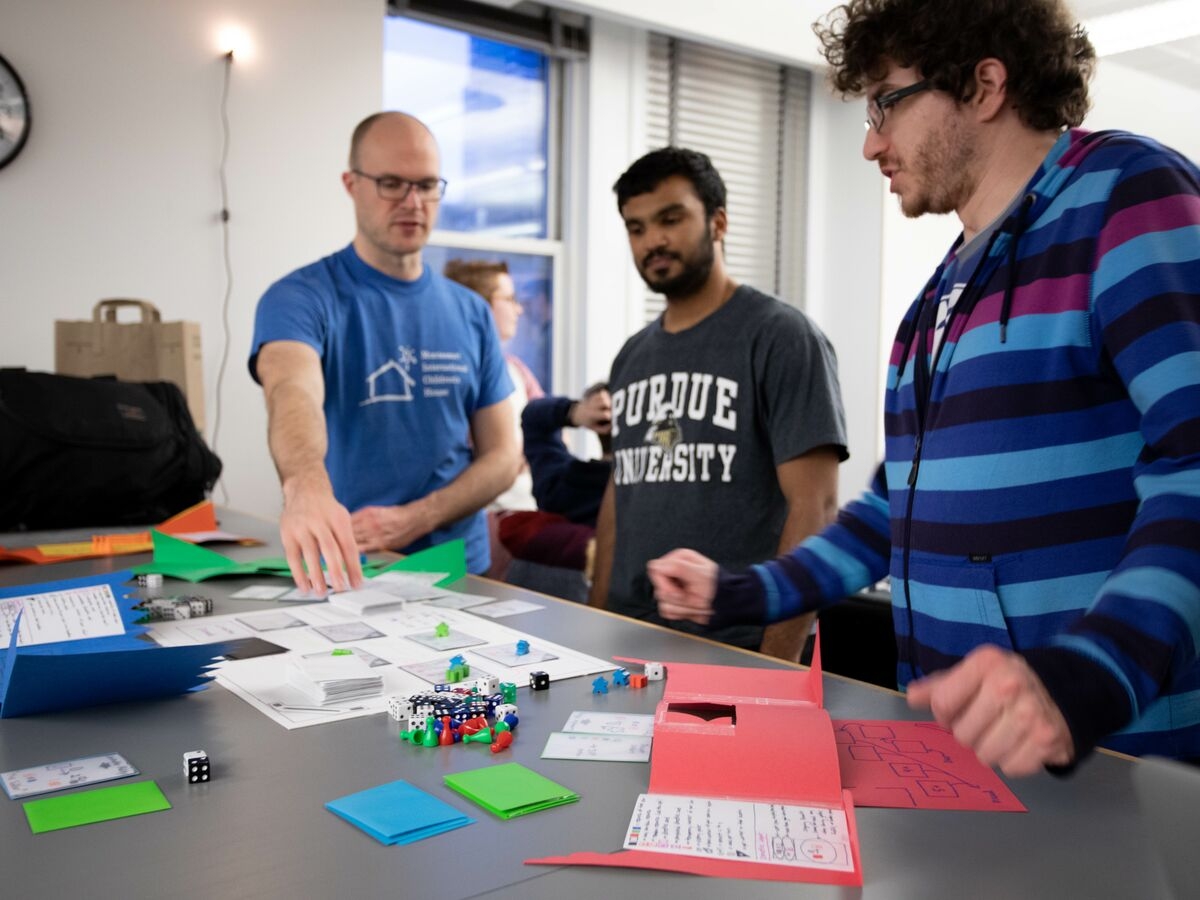 Three students discuss and play a game with dice during the Global Game Jam