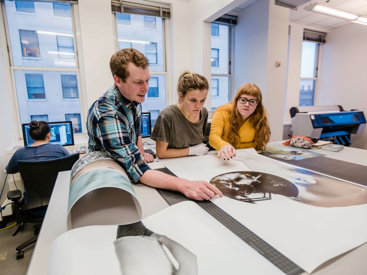 Students inspect a printed poster on a table