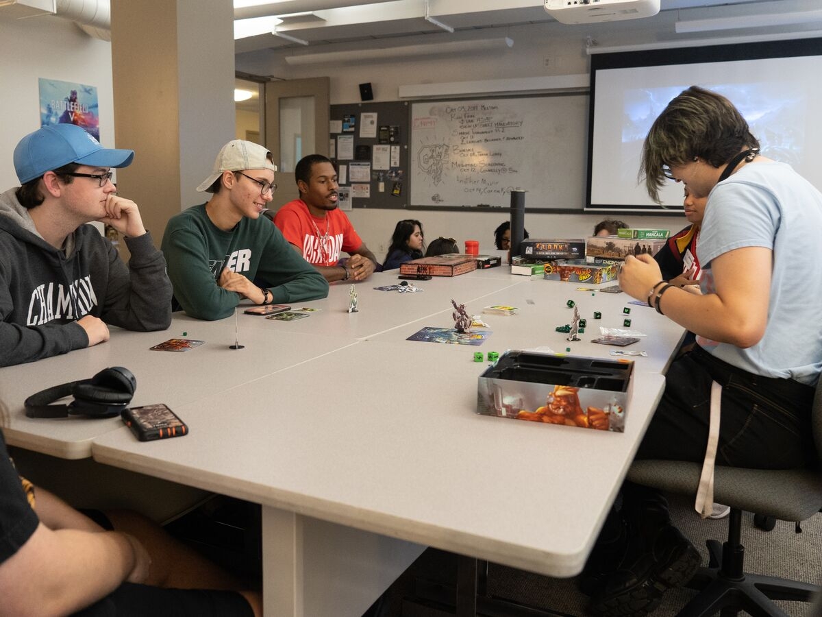 Students discuss and play a game with figures and dice during UArts day