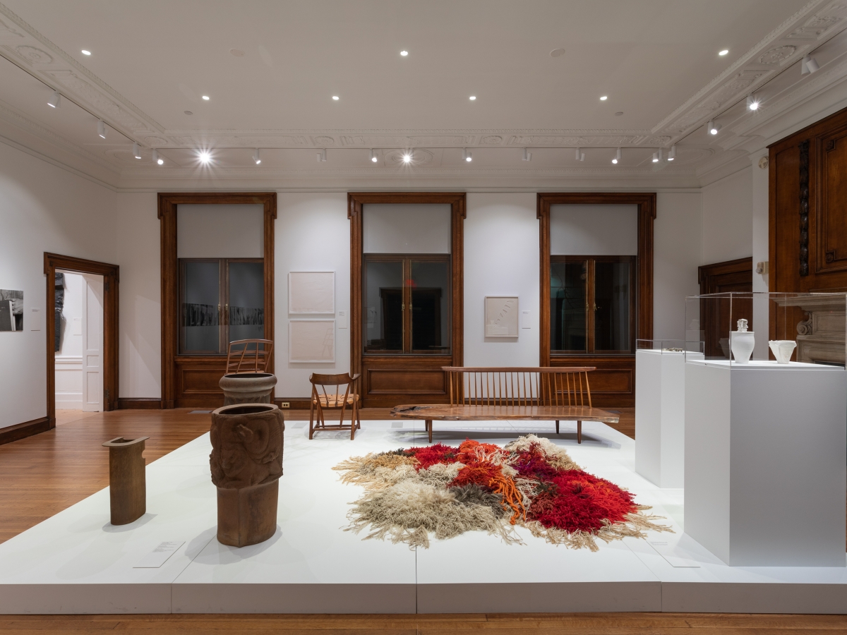  Invisible City Exhibition, Gallery B: raised platform in foreground displaying wooden furniture, pots, vases and a large fiber work  with large windows in the background