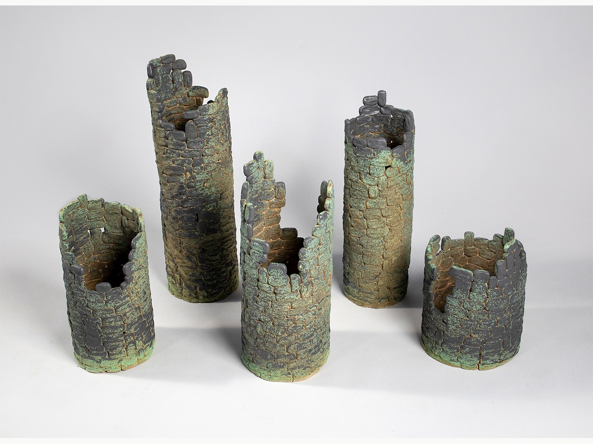 A set of stoneware that resembles circular brick columns with open tops made of stoneware with a green glaze