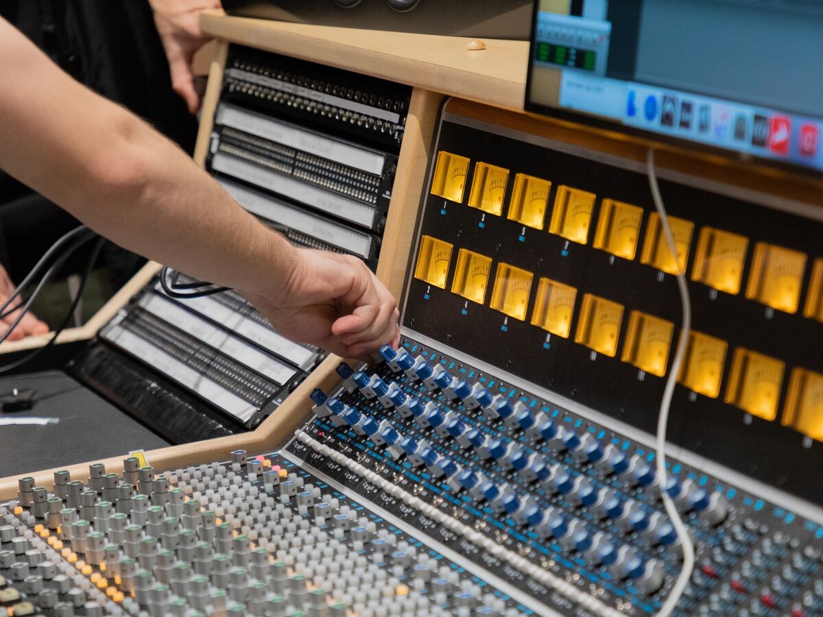 Students mix sound on the mixing board in the recording studios