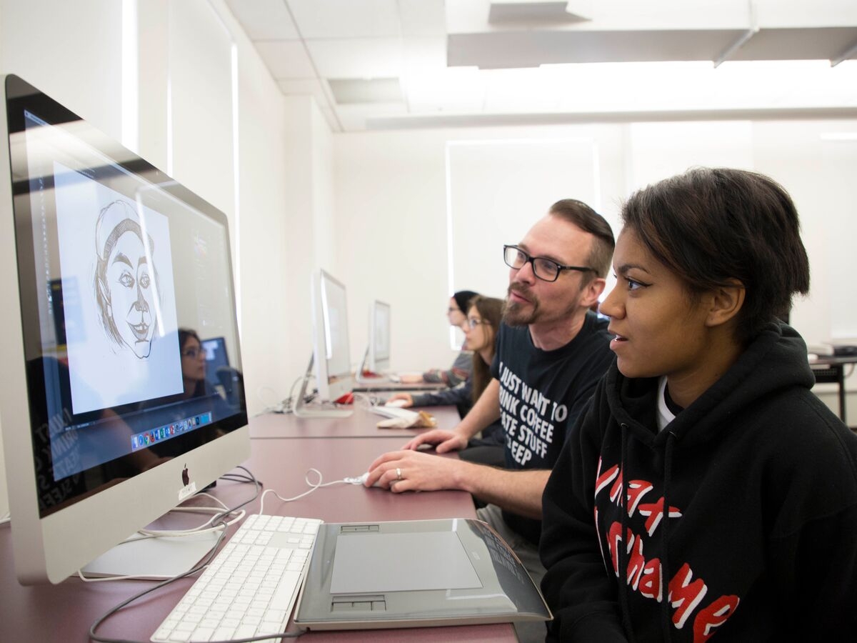 An Illustration student works with their teacher on their computer