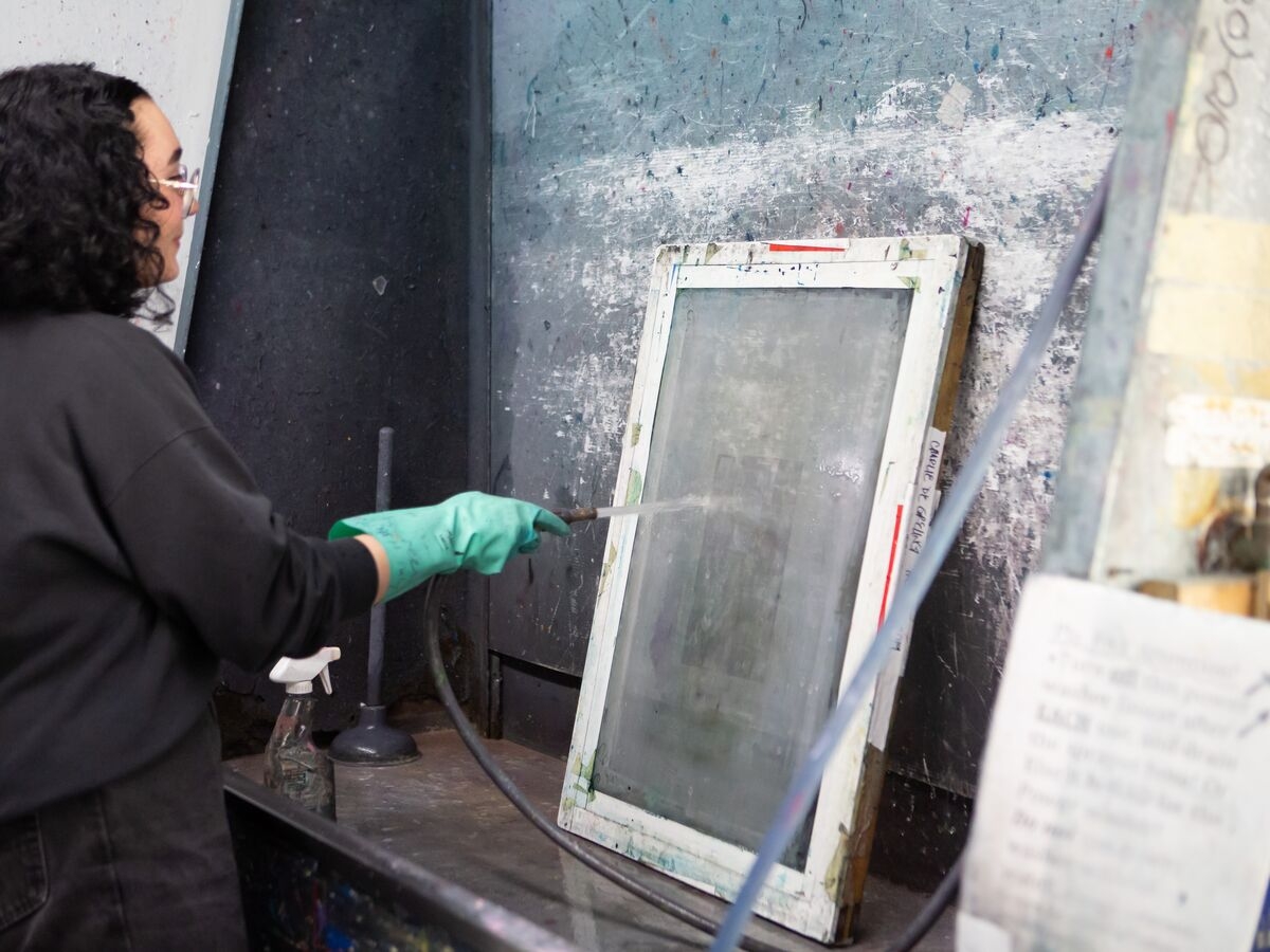 A Screenprinting student cleans their screen at the washing station