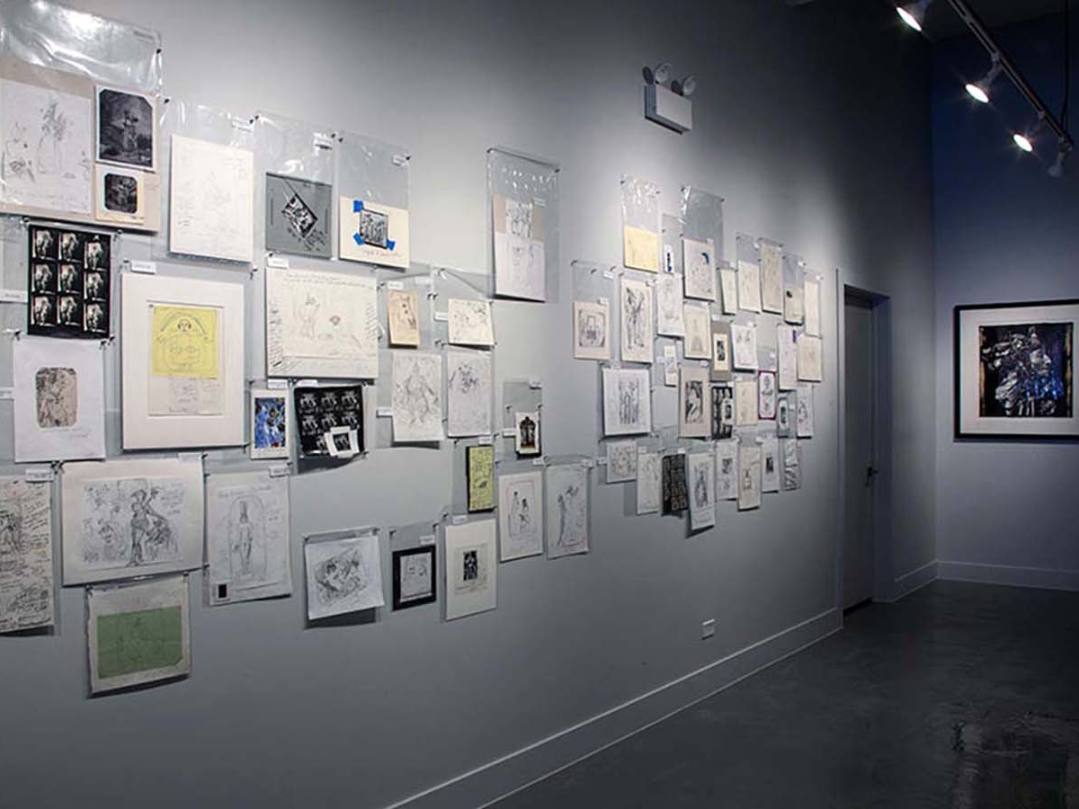 Installation view of Joel-peter Witkin: From The Studio at Catherine Edelman Gallery. Various ephemera including photographs, documents and sketches are pinned to the white, gallery walls in clear plastic bags.