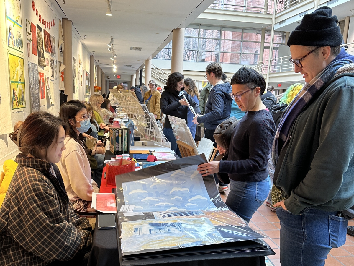 Students presenting work at table during printPHILLY fair