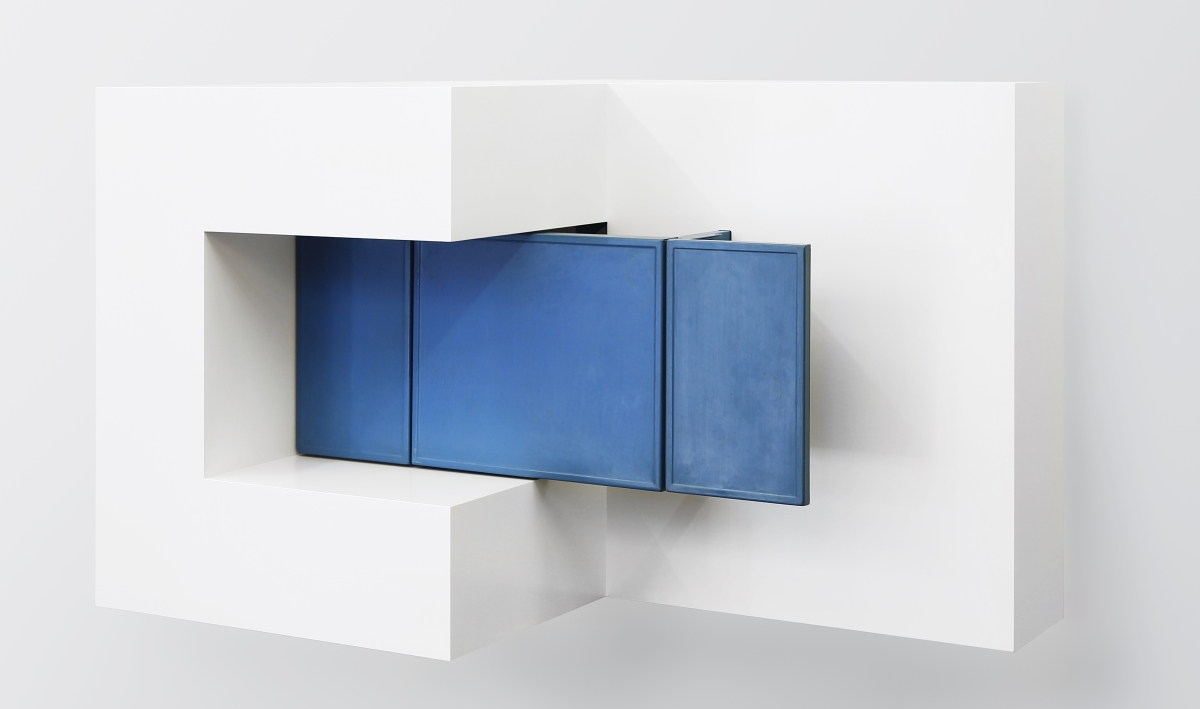 Wall sculpture with blue cabinet in middle of white cube-like structure