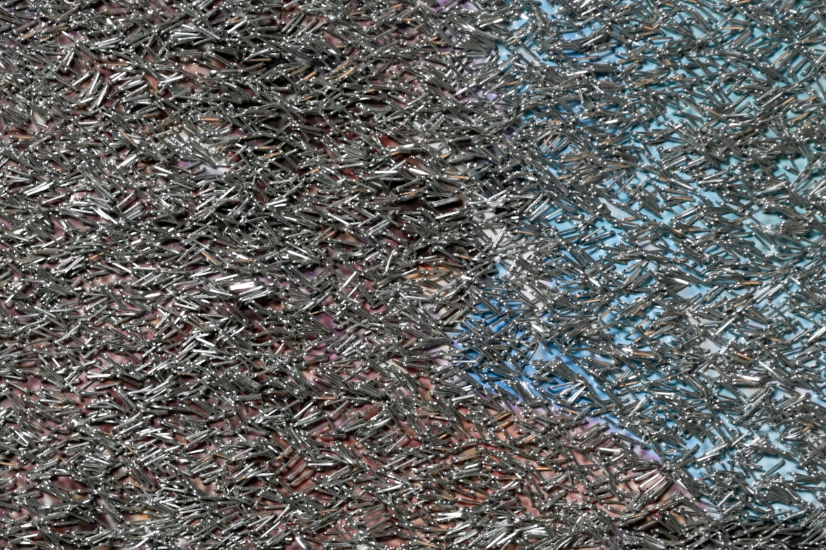 Detail image of artwork that has a color image almost obscured by staples