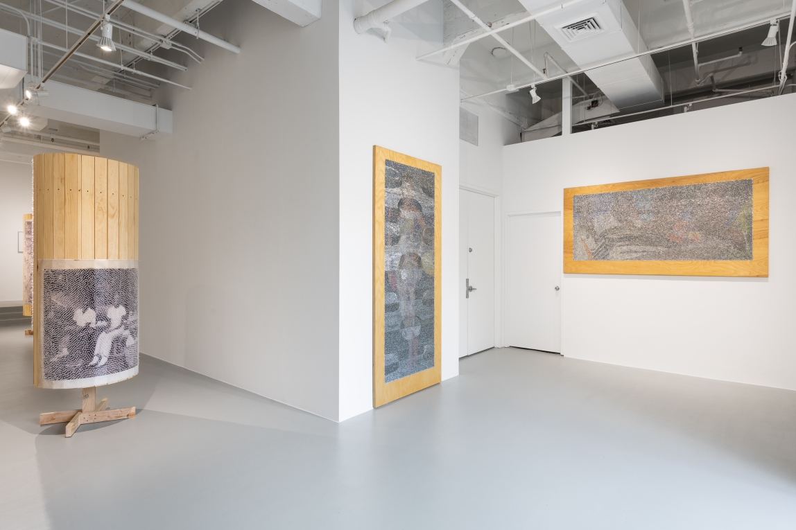Installation view with two large wall works to the right, a wooden column with images to the left