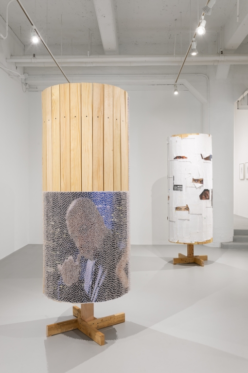 Closer image of wooden column with poster of man's face covered in tacks